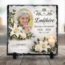 Fehér liliomokkal, rózsákkal, gyertyával és indás felső díszítéssel ellátott egyedi kegyeleti fotókő kitámasztó talpakon idős hölgy fotójával és saját idézet felirattal
