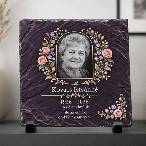 Koszorú elrendezésű rózsaszín rózsákkal, kék nefelejccsel és sarokdísszel díszített egyedi kegyeleti fotókő kitámasztó talpakon sötétlila háttérrel és Kovács Istvánné felirattal